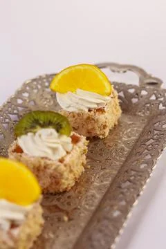 Three delicate bite-sized square cake pieces topped with whipped cream Stock Photos