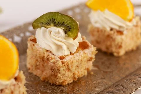 Three delicate bite-sized square cake pieces topped with whipped cream Stock Photos