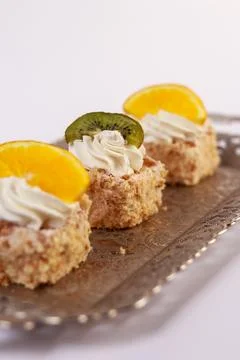 Three delicate bite-sized square cake pieces topped with whipped cream Stock Photos