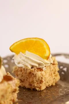 Three delicate bite-sized square cake pieces topped with whipped cream Stock Photos