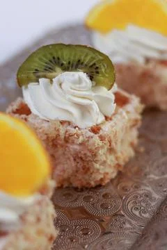 Three delicate bite-sized square cake pieces topped with whipped cream Stock Photos