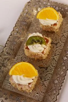 Three delicate bite-sized square cake pieces topped with whipped cream Stock Photos