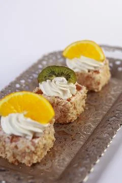 Three delicate bite-sized square cake pieces topped with whipped cream Stock Photos