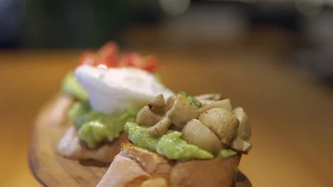 Three delicious bruschettas with white crusty bread on a tray, avocado covers Vidéo 256143311