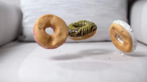 Three delicious donuts pounce on the surface of the light chair in slow motion. Stock Footage 191001687