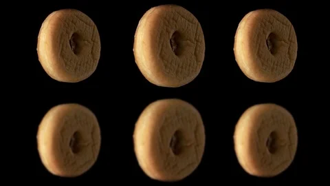 Three delicious donuts rotate on a black background. Donuts spin on a mirror Vidéo 125831437