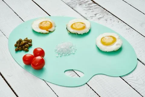 Three delicious fried egg tomatoes and basil leaves on chopping board Stock Photos