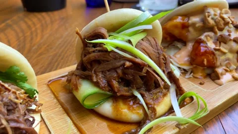 Three delicious hot steam bao buns with pulled pork, coriander and crispy Stock Footage 250608099