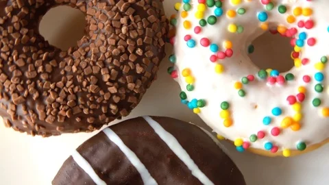 Three delicious sweet donuts rotating on a white plate. Looped Stock-Footage 70789242