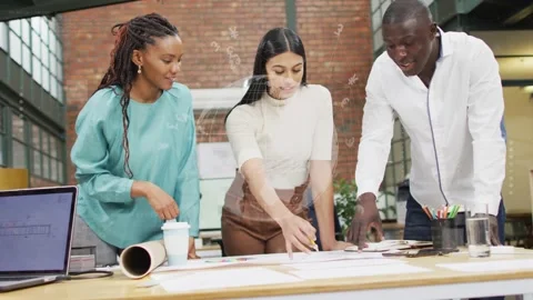 Three designers leaning over table, center reaching, aligning layouts and Stock Footage 334322108