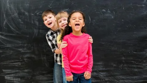 Three different children stand one by one peeking out from behind each other Foto stock