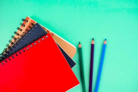 Three different colored note paper diary and pencil crayon placed beside each Stock Photos