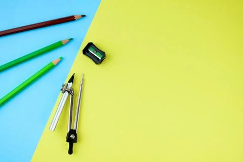 Three different colored pencil crayons along side a black pencil sharpener an Stock Photos