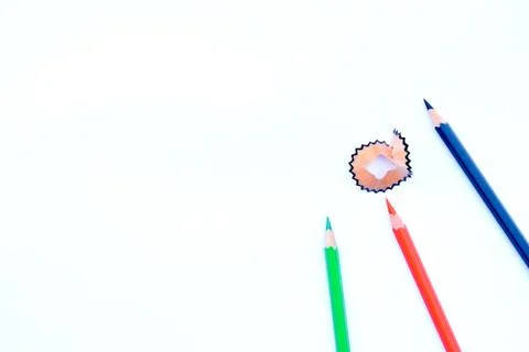 Three different colored pencil crayons and a pencil shaving scattered on a wh Stock Photos