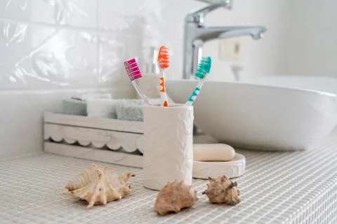 Three different colored toothbrushes stand in a ceramic glass Stock Photos