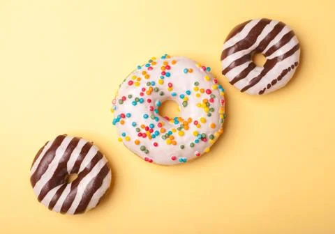 Three different donuts isolated on yellow background Stock Photos