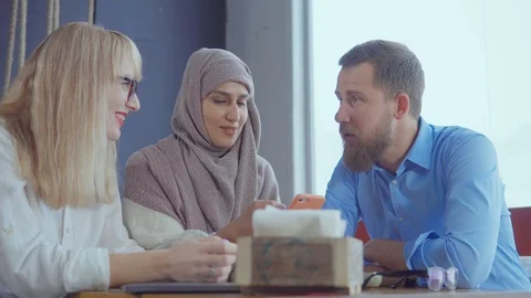 Three different ethnic friends man and women are chatting in cafe in daytime Stock Footage 104666919
