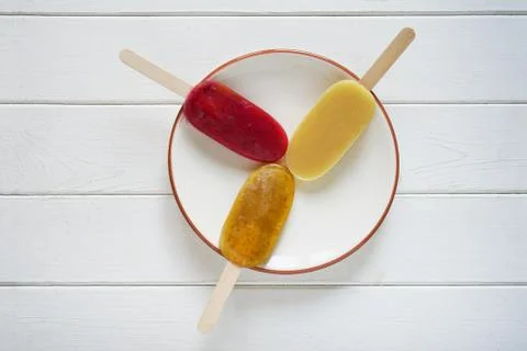 Three different fruit smoothie popsicles or ice pops on a plate Stock Photos