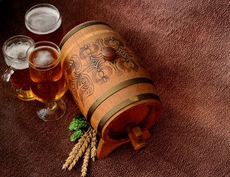 Three different glasses with light beer, a wooden keg, ears of malt and hops Stock Photos