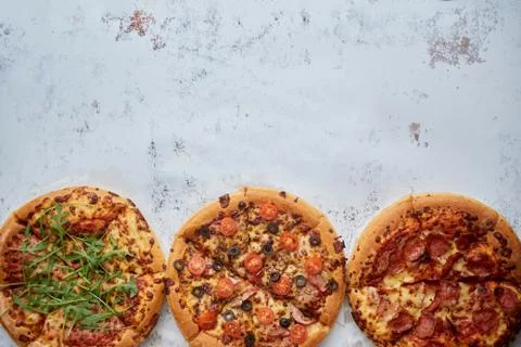 Three different kind of pizzas placed in a row on white rusty table Stock Photos