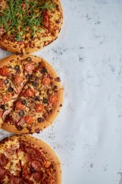 Three different kind of pizzas placed in a row on white rusty table Stock Photos