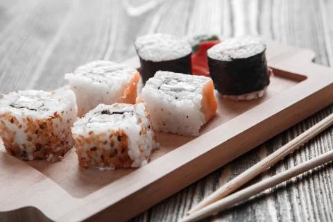 Three different kinds of Japanese rolls with wasabi and ginger on bamboo tray Stock Photos