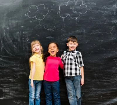 Three different laughing children with blackboard on background Foto stock