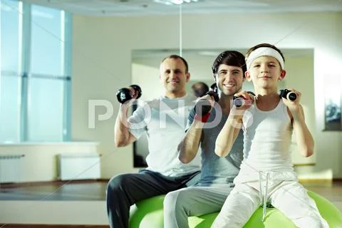 Three different males exercising with dumbbells in gym Stock Photos
