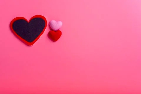 Three different size red heart on left hand side in pink background. valentin Foto stock