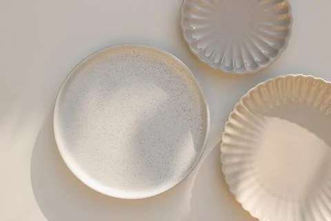 Three different size stoneware plates on beige table background. Flat lay, top Photos