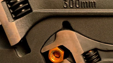 Three different sized adjustable wrenches, each holding a steel nut. Stock Footage 278906791