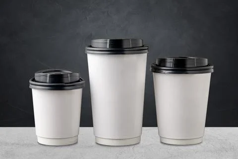 Three different sizes of white takeaway paper cups with black plastic lids is Stock Photos