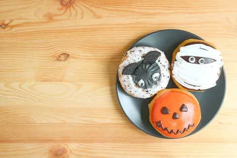 Three Different Types of Halloween Doughnuts on Black Plate Served on Woode.. 스톡 사진