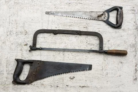 Three different used saws in white rustic wooden background Stock Photos
