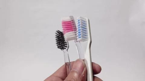 Three differently colored toothbrushes held against a white background Stock Footage 313988278