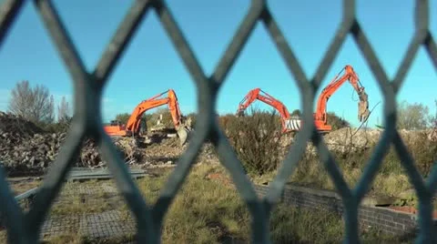 Three diggers through fence on demolition site Stock Footage 14819556
