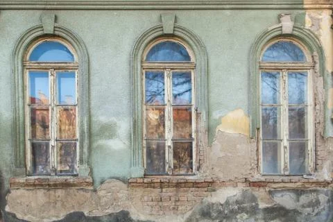 Three dilapidated windows on the old hobbled home Stock Photos