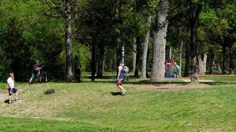 Three disc golf players on the putting green are making their putt throws Vídeo Stock 156833555