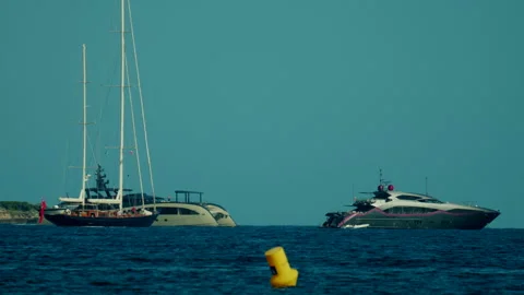 Three distinct vessels, including luxury yachts and a classic sailboat, navigate Stock Footage 339804566