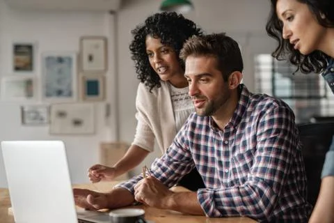 Three diverse designers using a laptop together at work Stock Photos