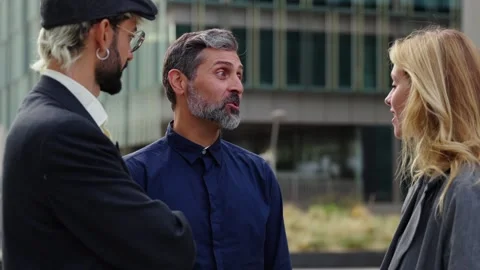 Three diverse formal co-workers standing outside office building talking relaxed Stock Footage 273094772