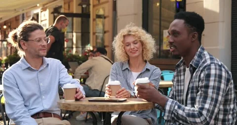 Three diverse friends friendly chatting and drinking coffee at table in cafe Stock Footage 161816669