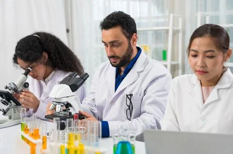 Three diverse scientists in lab coats conducting research Stock Photos