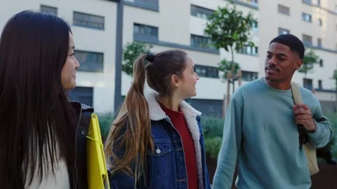 Three diverse student friends hanging out while walking at college campus Stock Footage 288635835