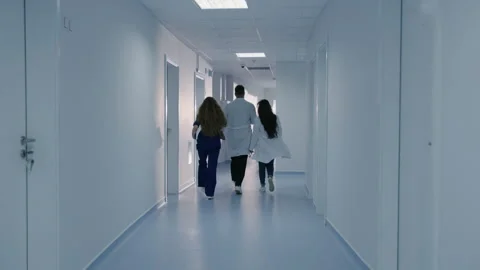 Three doctors are rushing down the corridor to an emergency call Stock Footage 230237226