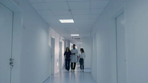 Three doctors are walking down the corridor of the hospital Stock Footage 230247224