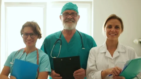 Three doctors at the clinic are smiling while standing opposite the window Stock Footage 118832482