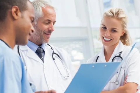 Three doctors examining a file Stock Photos