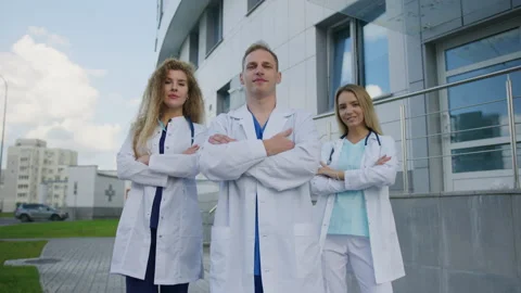 Three doctors look into the camera and pose outside the clinic Stock Footage 224056430