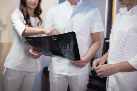 Three doctors look at an x-ray photo of a patient together Stock Photos